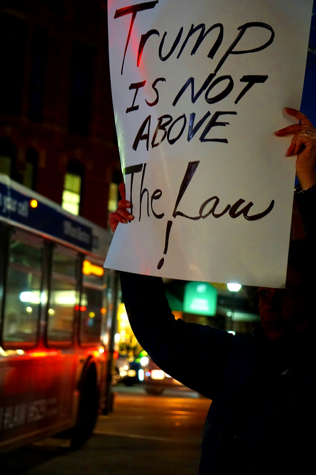 about-us-02 person-holding-trump-is-not-above-the-law-signage-hkltly7xl2c